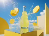 Lemon soda bottle surrounded by sliced lemons and splashing water on a yellow mirrored pedestal