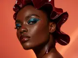 Beauty portrait with teal eye makeup and a sculptural burgundy headpiece
